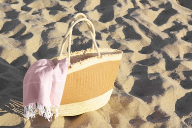 Photo of Stylish wicker beach bag and blanket on sand