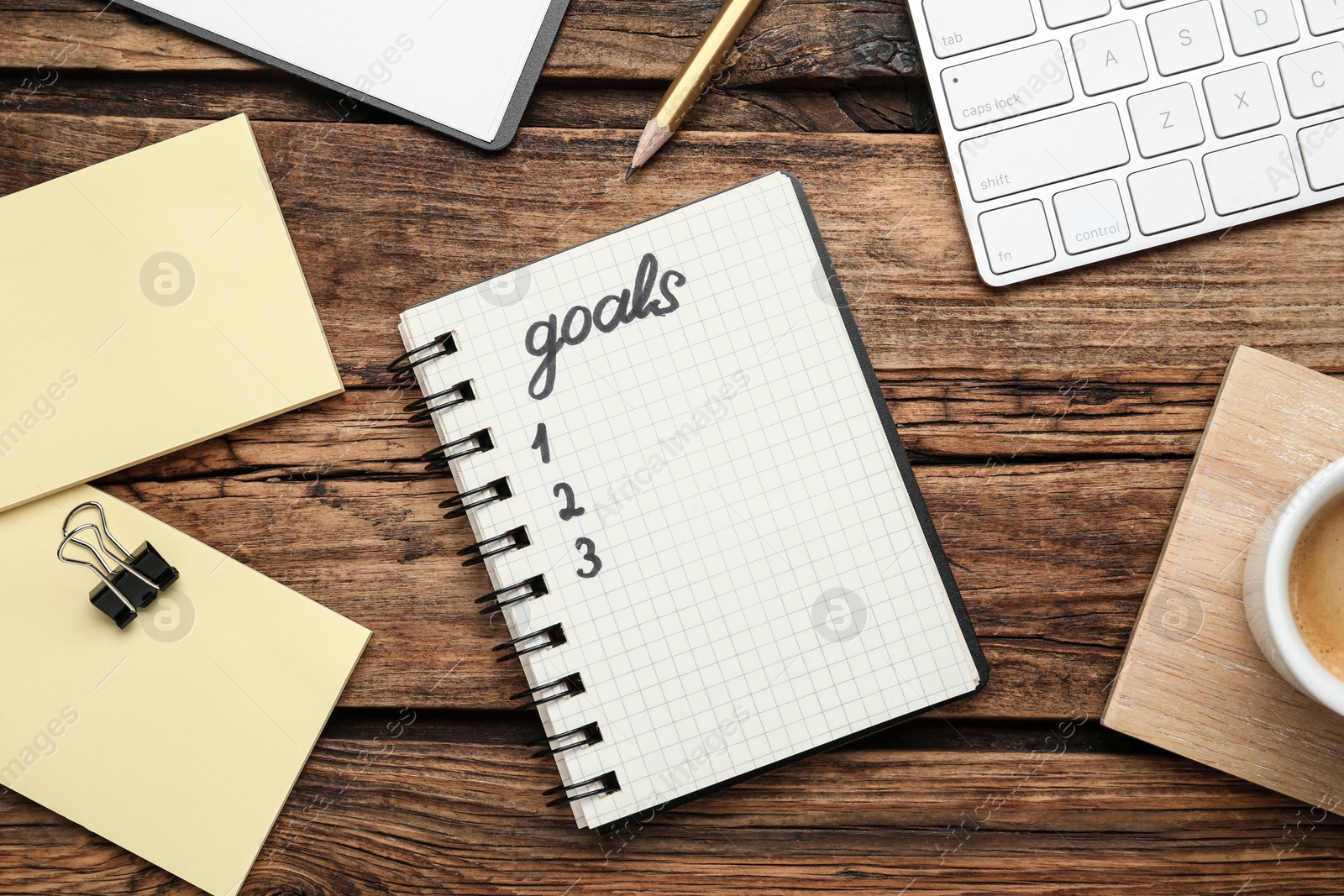 Photo of Flat lay composition with office stationery on wooden table. Word Goals in notebook