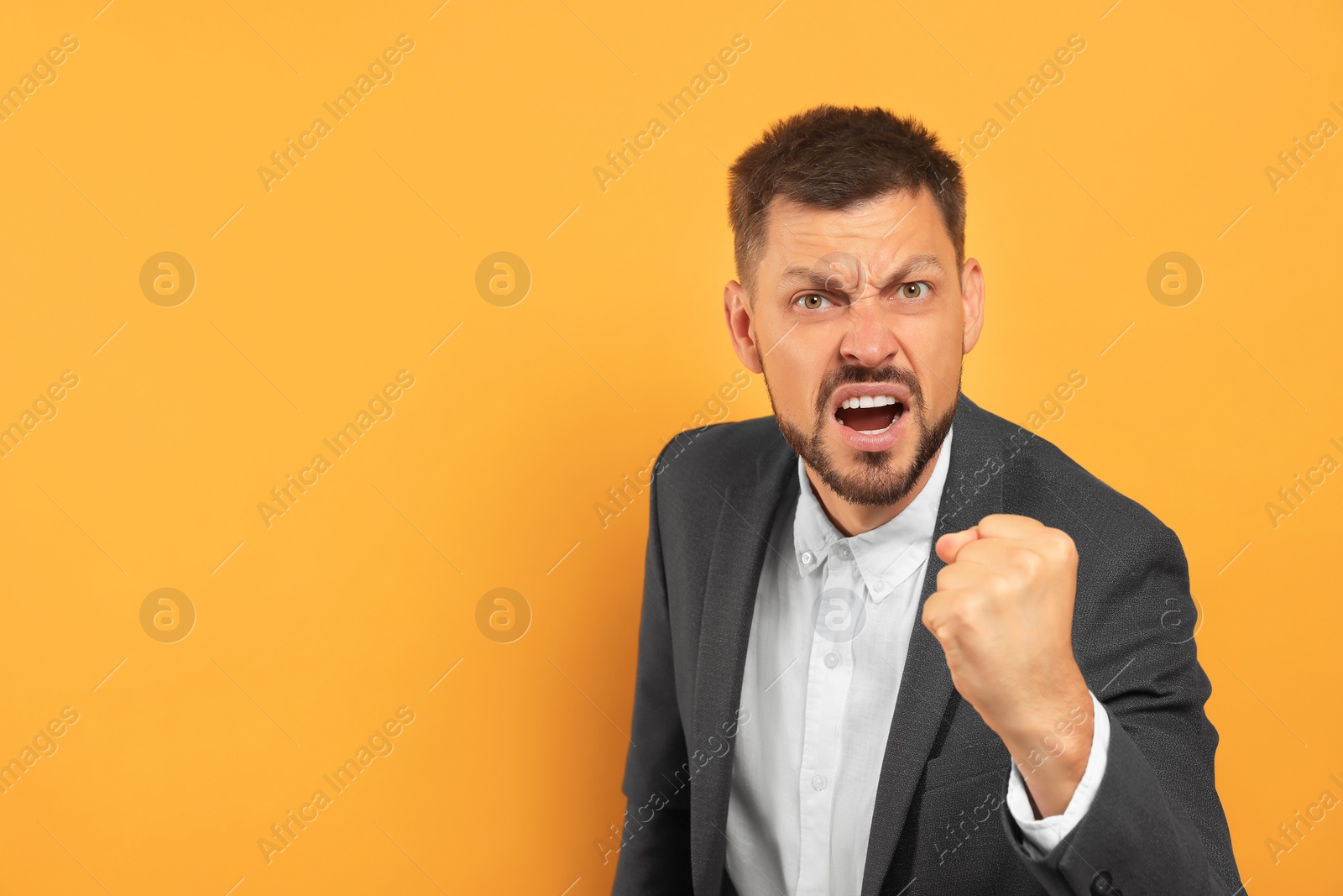 Photo of Aggressive man on orange background, space for text