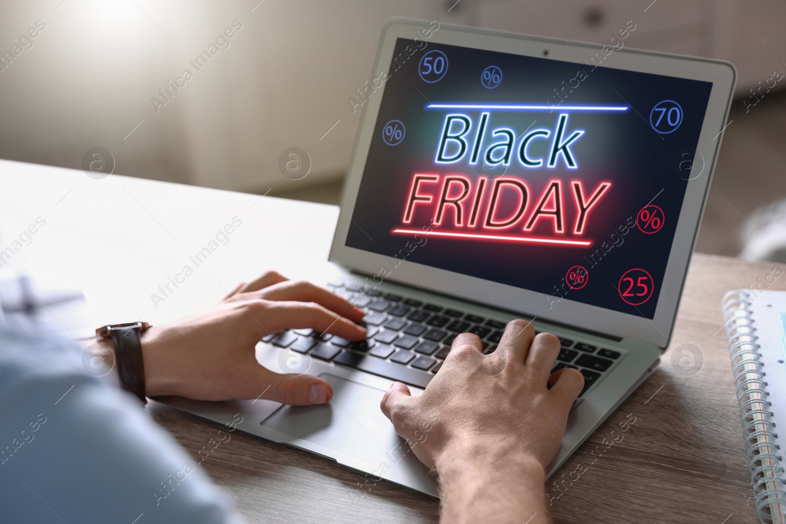 Image of Black Friday. Man shopping online using laptop at table, closeup