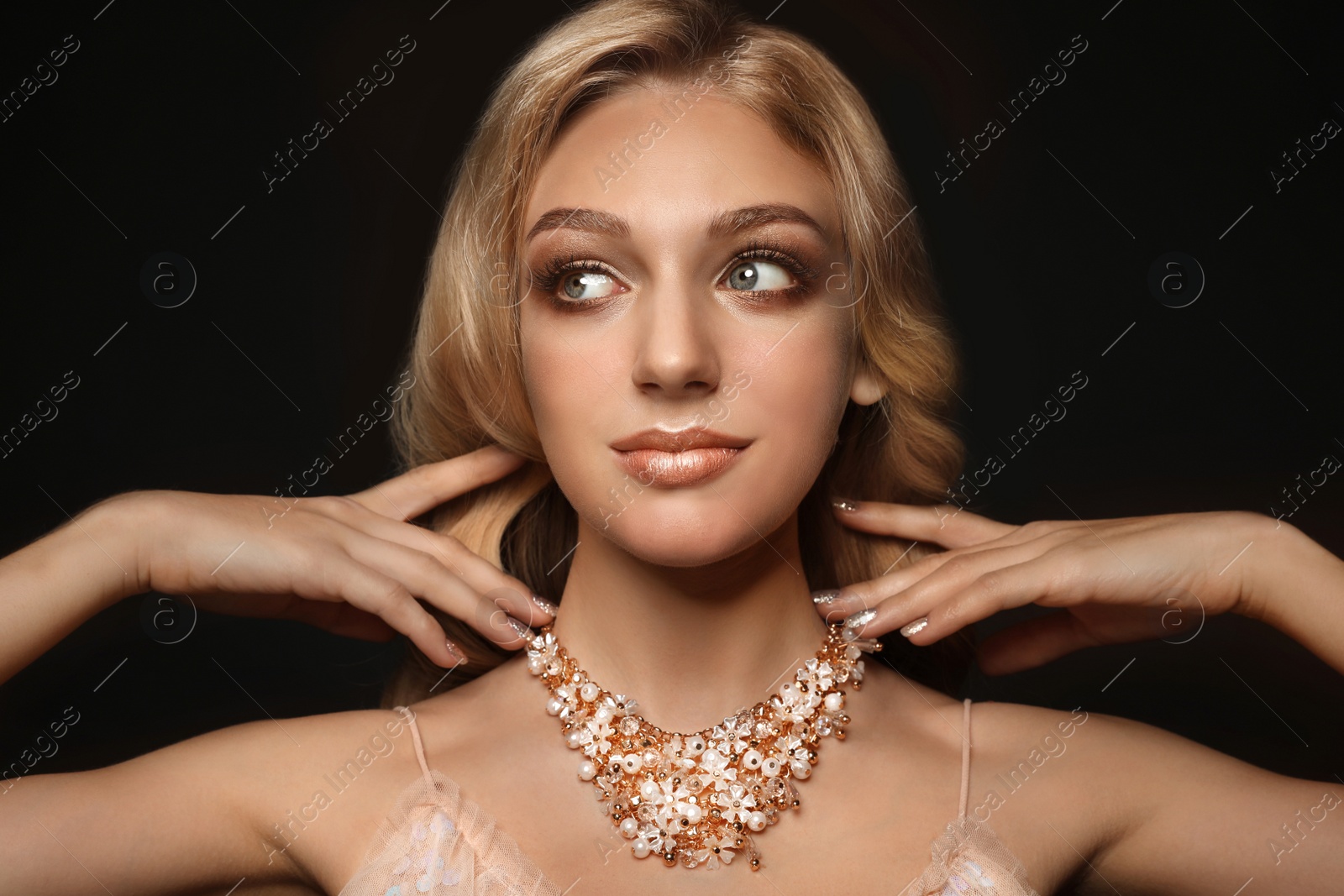 Photo of Beautiful young woman with elegant jewelry on dark background