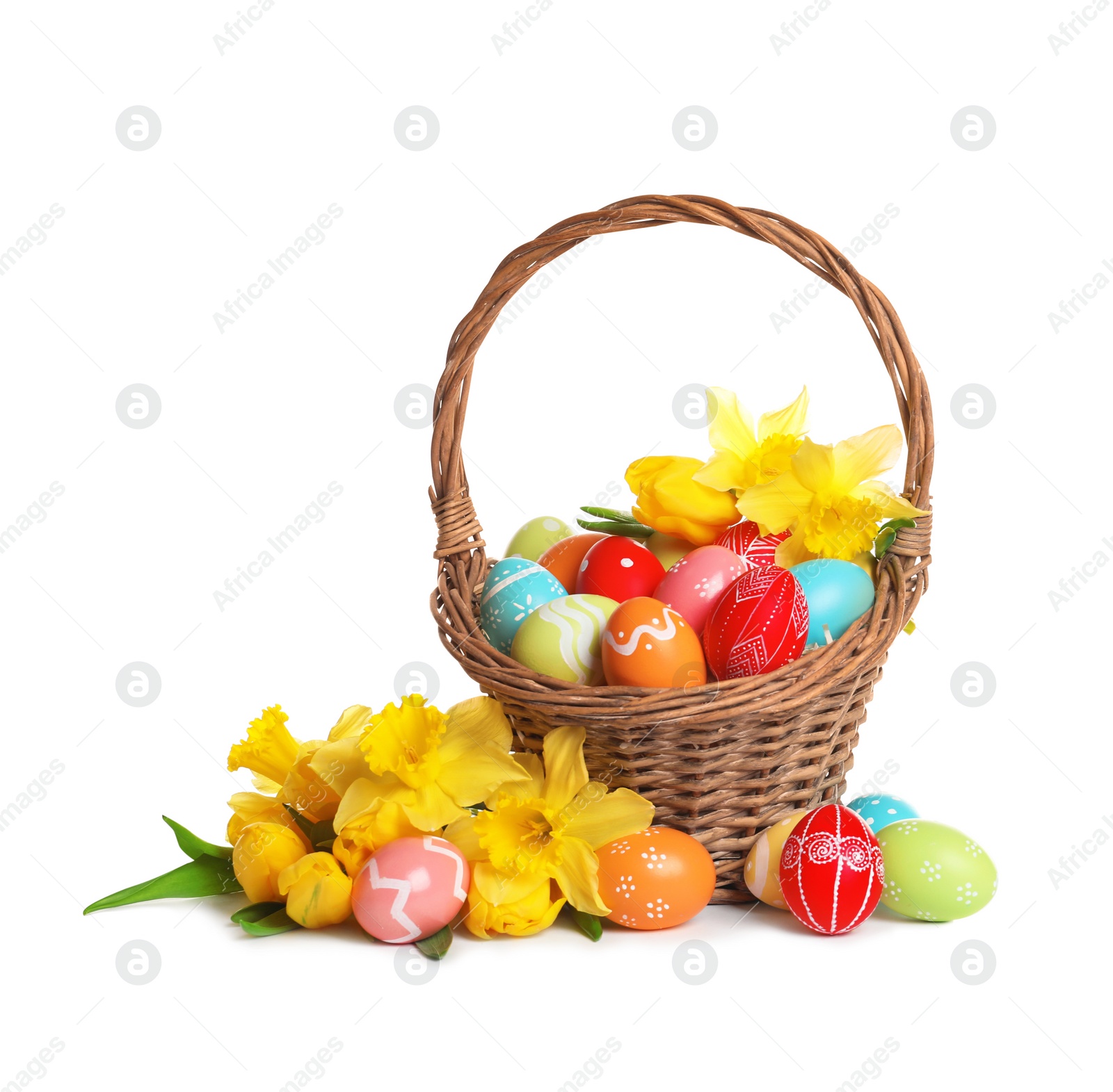 Photo of Wicker basket with painted Easter eggs and flowers on white background