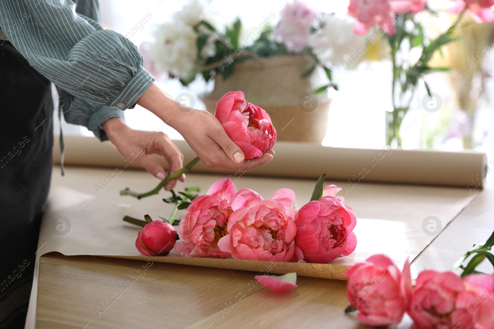 Photo of Florist making beautiful peony bouquet at table, closeup