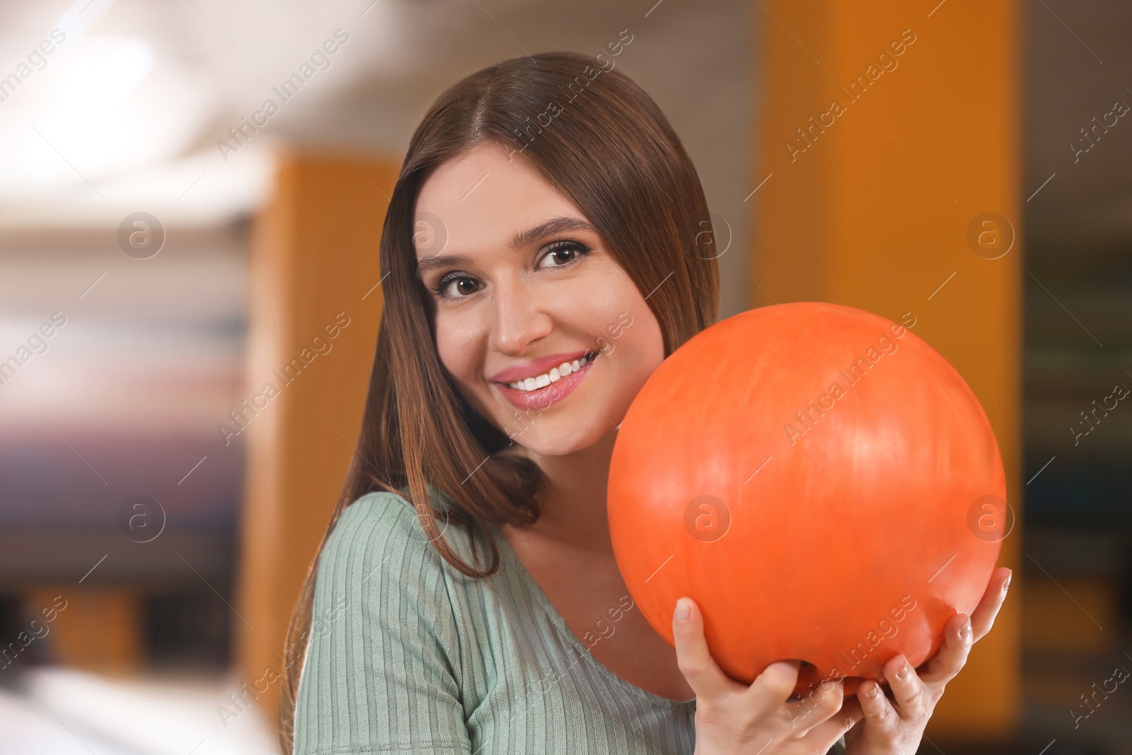 Photo of Young woman with ball in bowling club