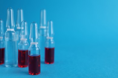 Photo of Many medical ampoules with solutions on light blue background. Space for text