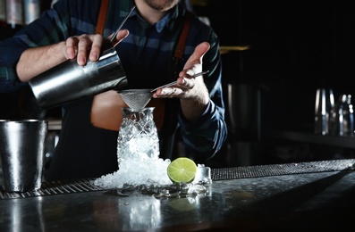 Barman making tropical cocktail at counter in pub, closeup. Space for text