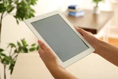 Photo of Young woman using new modern tablet indoors, closeup