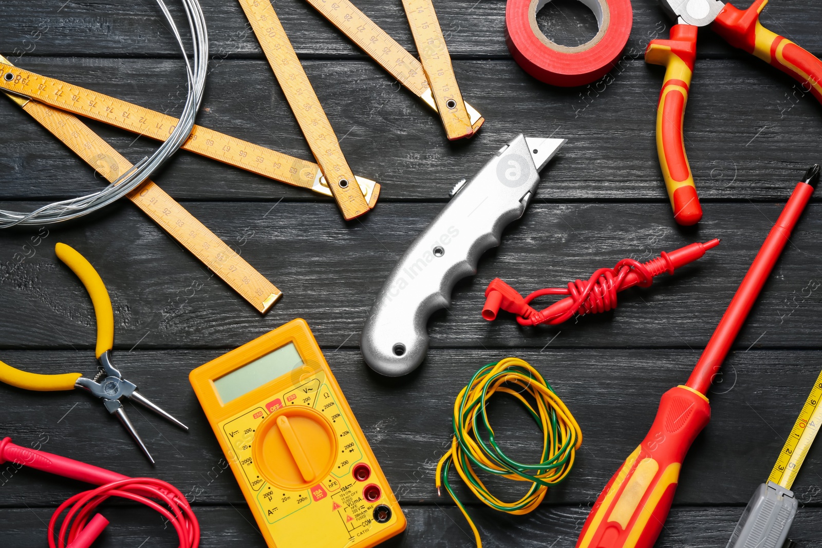 Photo of Different new wires and electrician's tools on black wooden table, flat lay