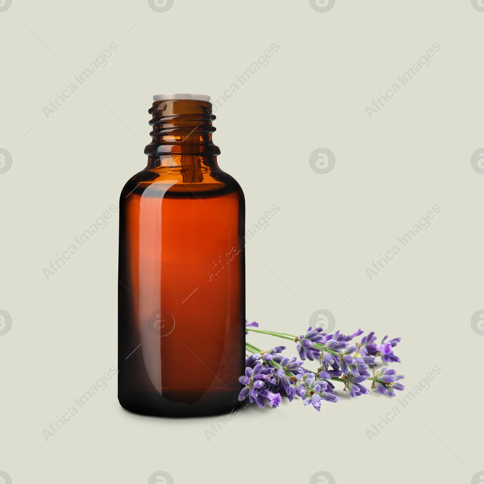 Image of Bottle of lavender essential oil and flowers on light background