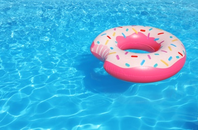 Inflatable ring floating in swimming pool on sunny day. Space for text