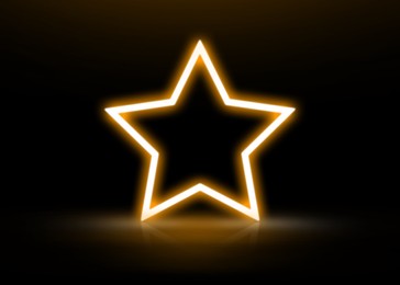 Glowing star-shaped orange neon frame on black background, space for text