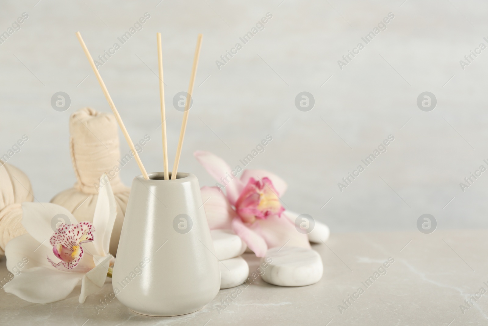 Photo of Beautiful composition with reed air freshener and spa stones on marble table. Space for text