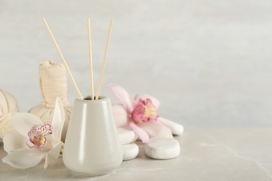 Beautiful composition with reed air freshener and spa stones on marble table. Space for text