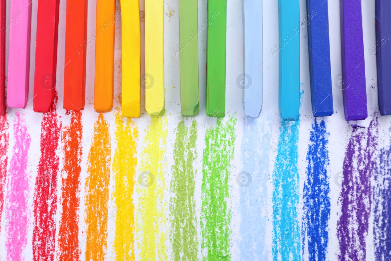 Photo of Colorful pastel chalks on white background, flat lay. Drawing materials