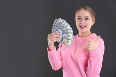 Photo of Portrait of happy young woman with money on grey background. Space for text