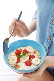 Photo of Woman eating delicious oatmeal with fruits, closeup. Healthy diet