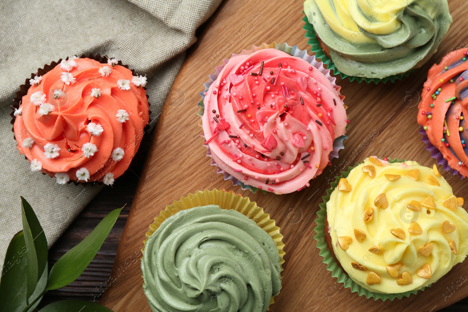 Photo of Delicious cupcake with bright cream on wooden table, flat lay