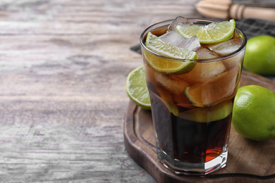 Photo of Glass of fresh Cuba Libre cocktail on wooden table, closeup. Space for text