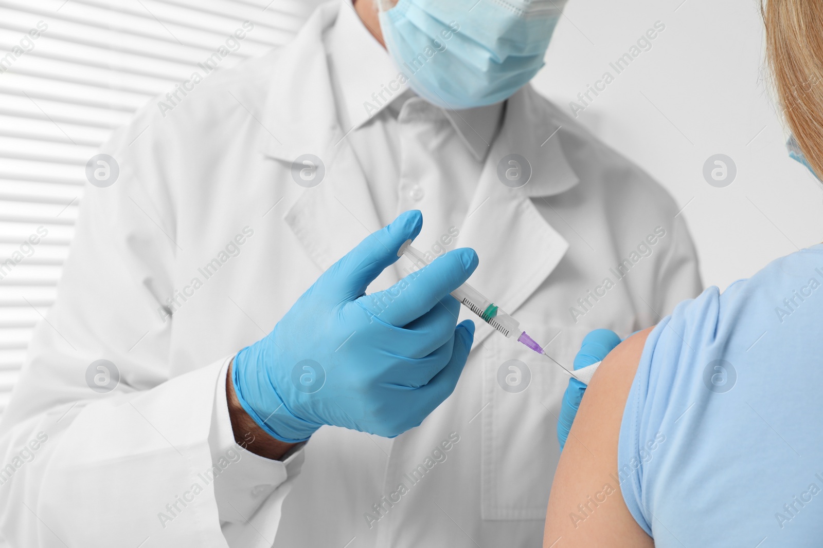 Photo of Doctor giving hepatitis vaccine to patient in clinic, closeup