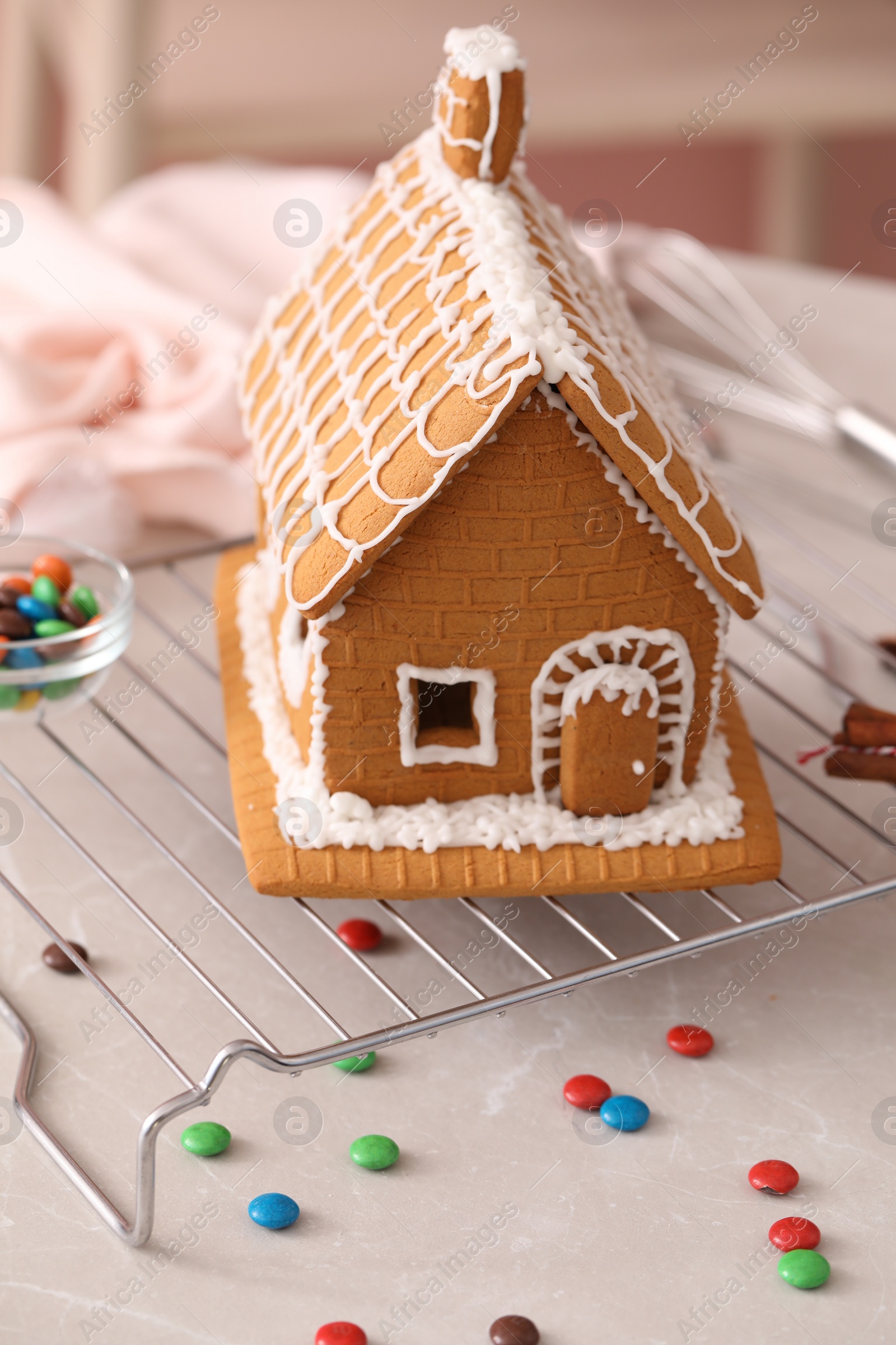 Photo of Beautiful gingerbread house decorated with icing on light grey marble table