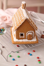Photo of Beautiful gingerbread house decorated with icing on light grey marble table