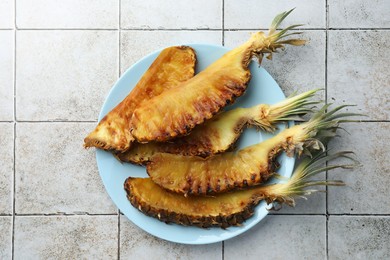 Tasty grilled pineapples on light gray tiled table, top view