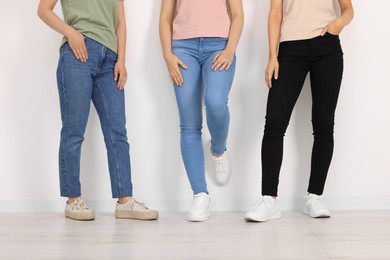 Photo of Women in stylish jeans near white wall, closeup