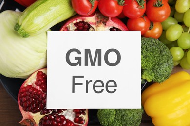 Tasty fresh GMO free products and paper card on table, top view