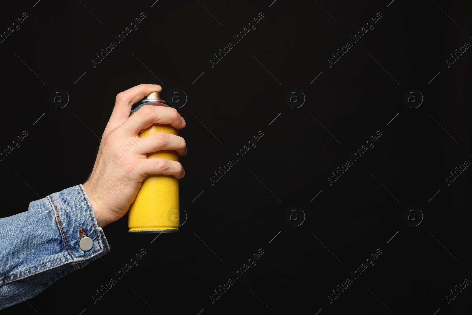 Photo of Man holding used can of spray paint on black background, closeup. Space for text