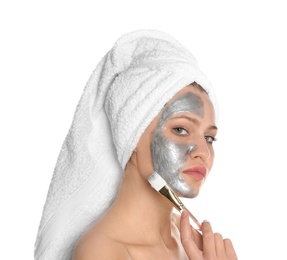 Beautiful woman applying silver mask on her face against white background