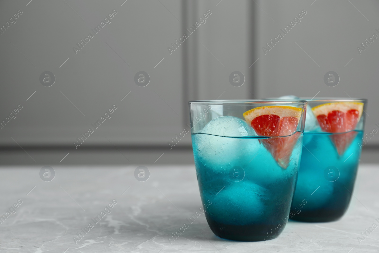 Photo of Delicious cocktails with grapefruit and ice balls on grey table, space for text