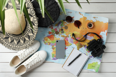 Photo of World map and items on white wooden background, flat lay. Travel during summer vacation