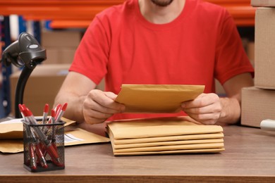 Photo of Post office worker with adhesive paper bags at counter indoors, closeup