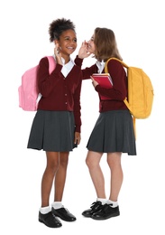 Happy girls in school uniform gossiping on white background