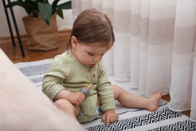 Cute baby girl with nibbler on floor at home