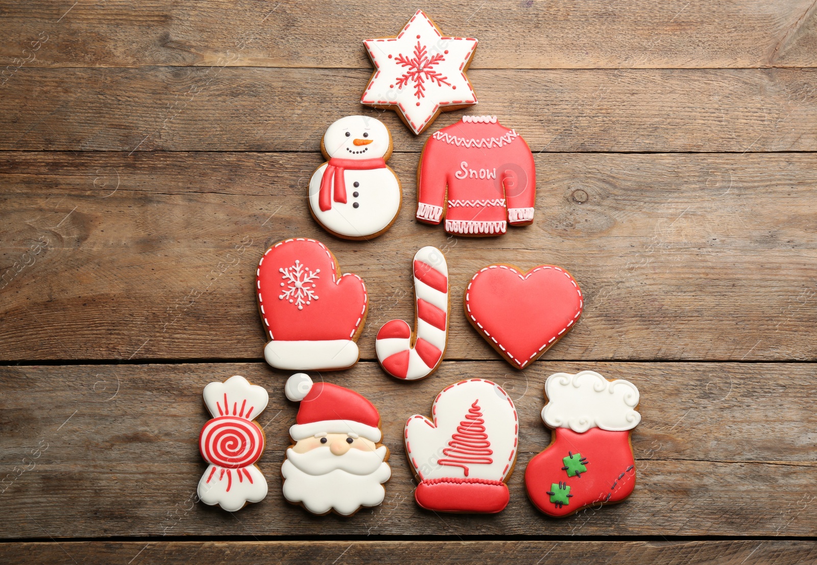 Photo of Christmas tree shape made of delicious decorated gingerbread cookies on wooden table, flat lay