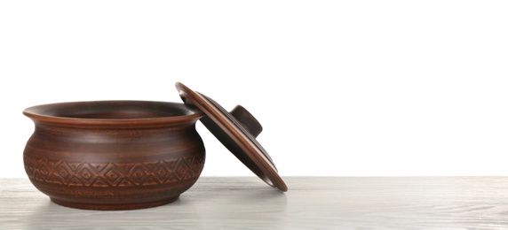 Photo of Brown clay pot on wooden table against white background. Space for text