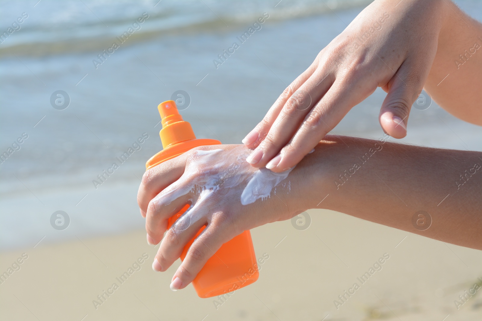 Photo of Woman applying sun protection cream on her hand at beach, closeup