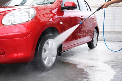 Photo of Male worker cleaning vehicle with high pressure water jet at car wash