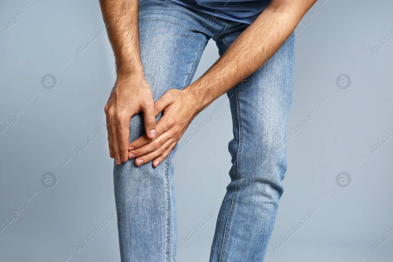 Photo of Man suffering from knee pain on grey background, closeup