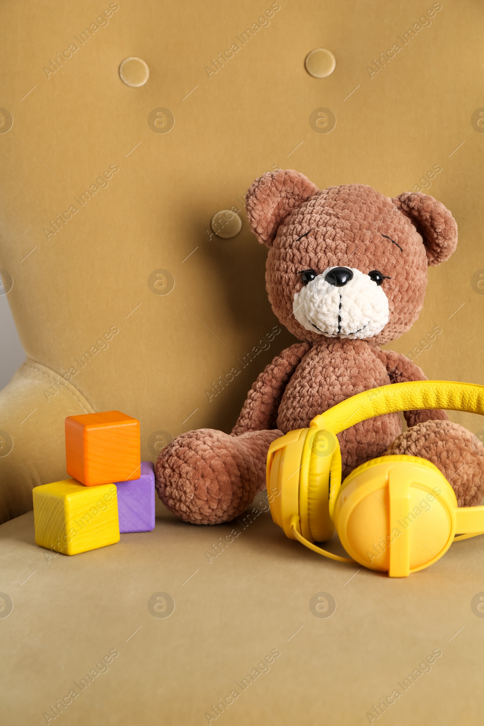 Photo of Baby songs. Toy bear, headphones and cubes on armchair