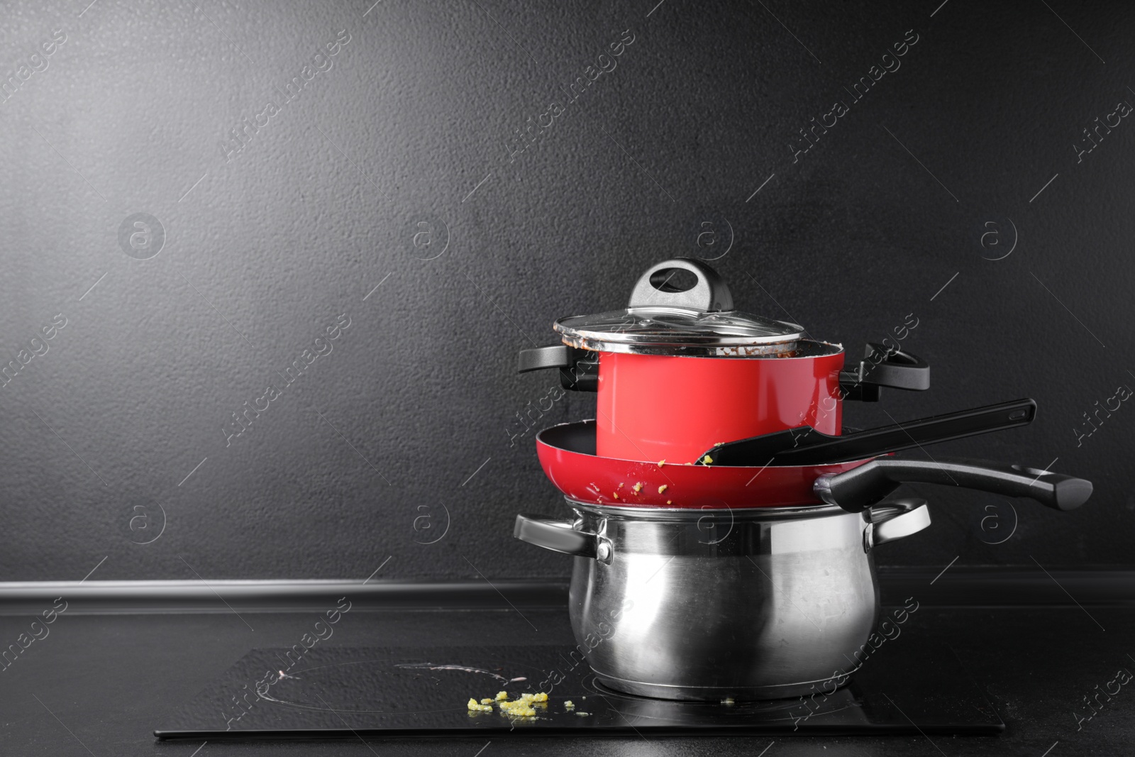 Photo of Stack of dirty kitchenware on cooktop in kitchen, space for text