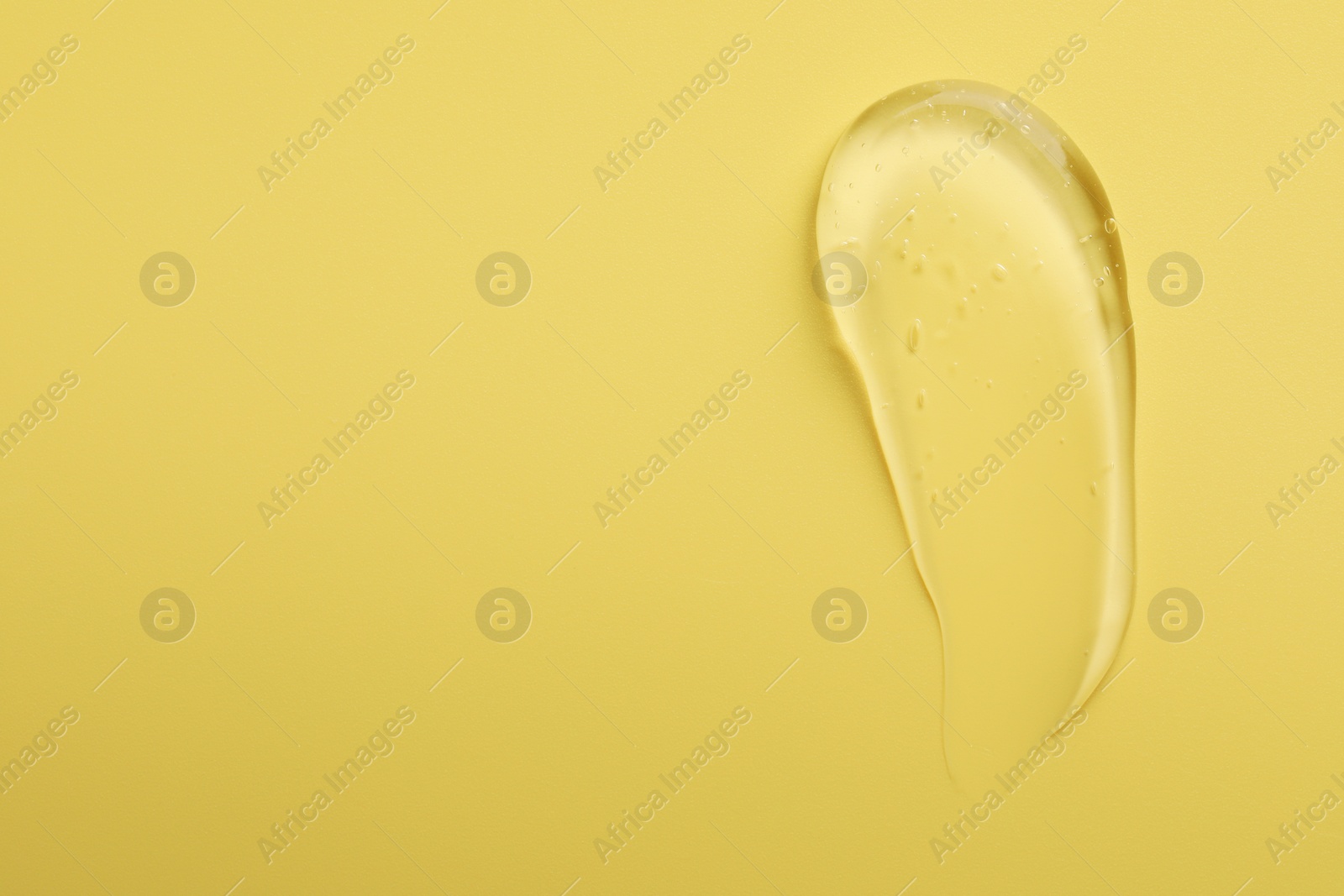 Photo of Smear of clear cosmetic gel on yellow background, top view. Space for text