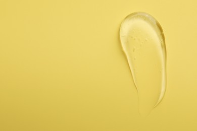 Photo of Smear of clear cosmetic gel on yellow background, top view. Space for text