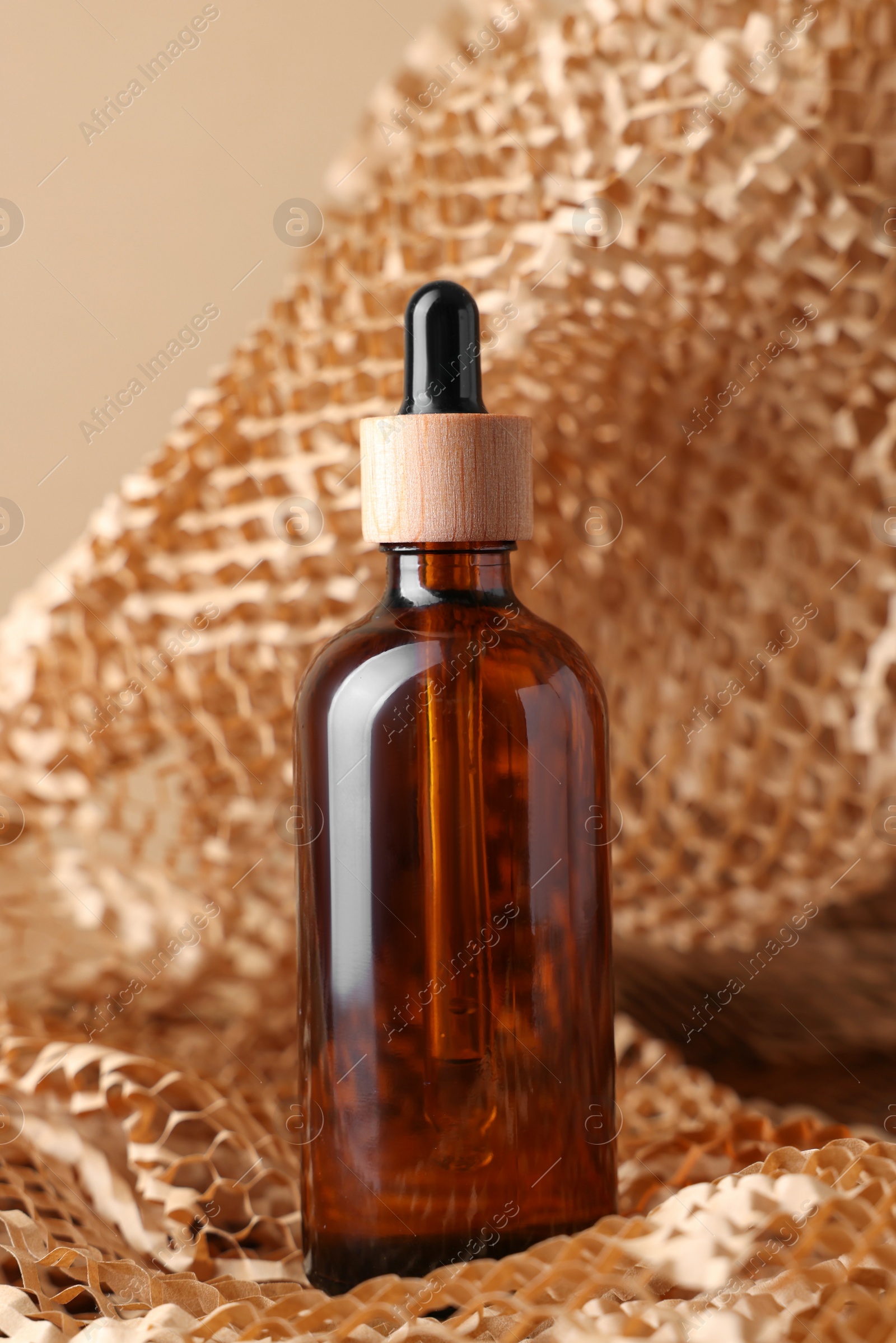 Photo of Glass bottle of cosmetic product on dark beige background