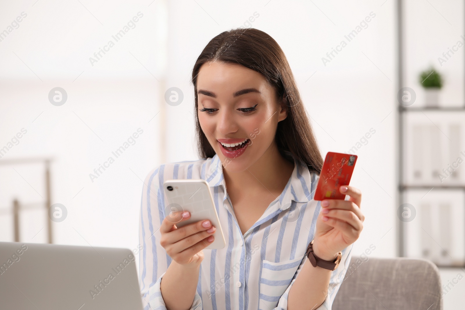 Photo of Woman with credit card using smartphone for online shopping indoors