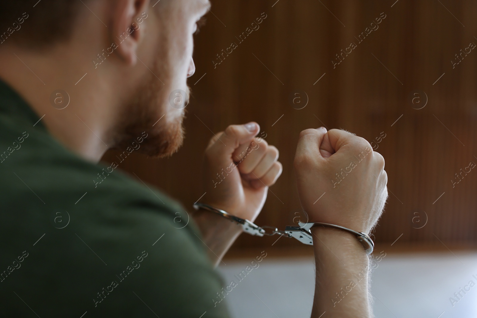 Photo of Man detained in handcuffs indoors, closeup view. Criminal law