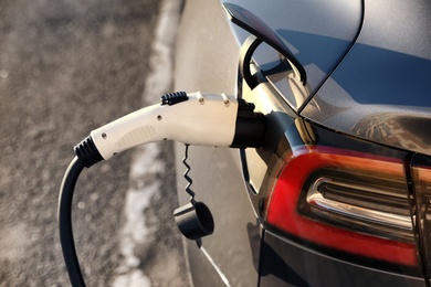 Photo of Charging modern electric car from station outdoors, closeup