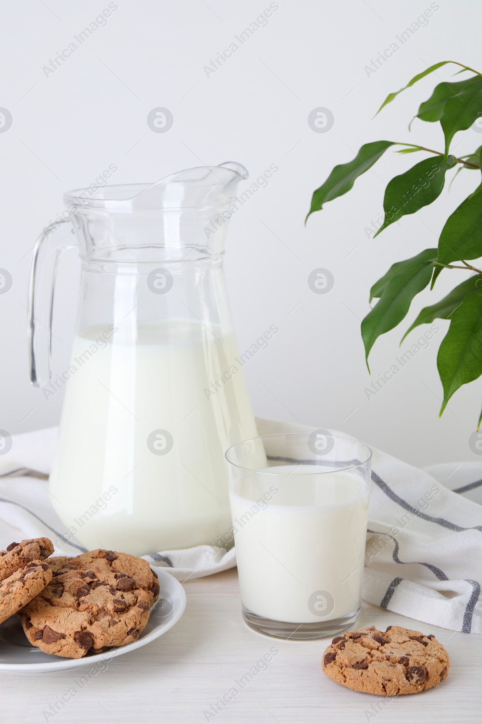 Photo of Jug of fresh milk, glass and cookies on wooden table