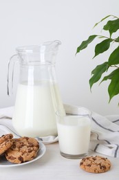 Photo of Jug of fresh milk, glass and cookies on wooden table